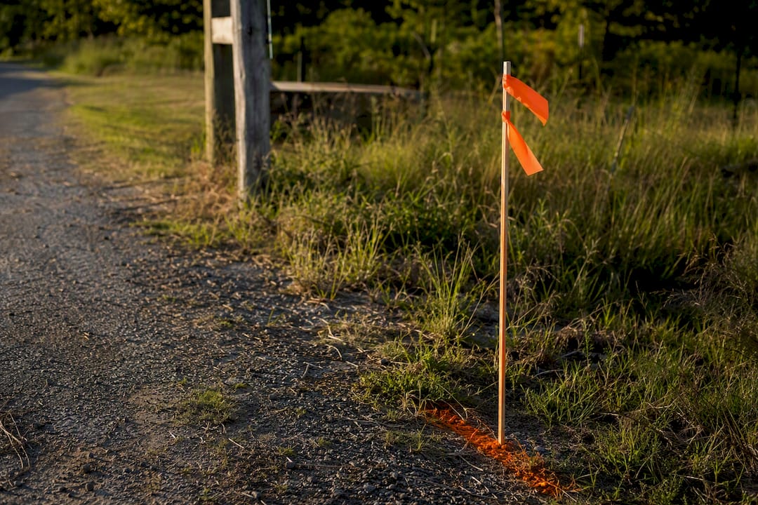 Stake with orange flags marking fence setback