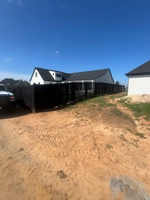Long run of black-stained wood privacy fence along a property line