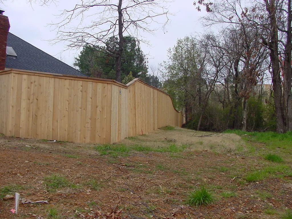 New wood privacy fence installed along a treeline