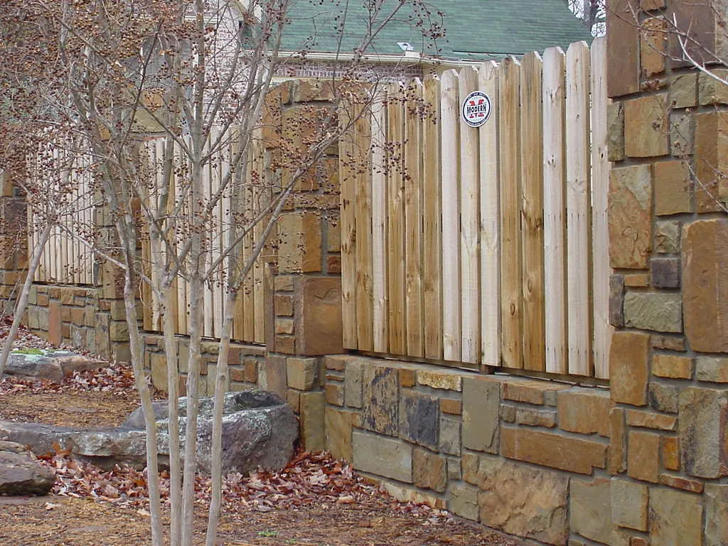 Wood fence meeting an existing stone retaining wall
