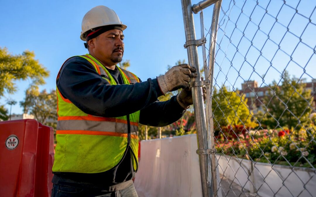 Worker installing temporary fence outdoors