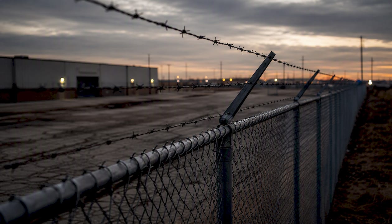 Tall chain link fence with barbed wire topper