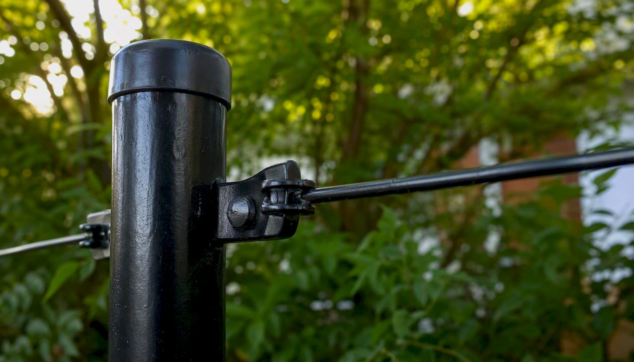 Black chain link fence post and tension wire clamps close-up